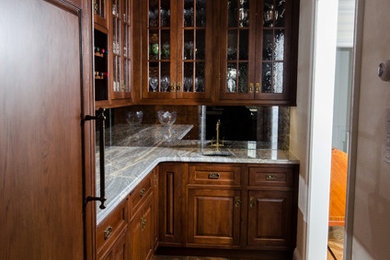 Wet bar - small traditional single-wall dark wood floor and brown floor wet bar idea in New York with an undermount sink, raised-panel cabinets, dark wood cabinets, granite countertops and mirror backsplash