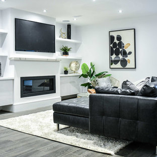 Inspiration for a contemporary walk-out basement in Toronto with white walls, medium hardwood flooring, a ribbon fireplace, a plastered fireplace surround and grey floors.