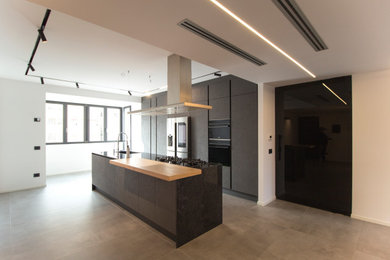 Photo of a large contemporary galley open plan kitchen in Catania-Palermo with an integrated sink, beaded inset cabinets, grey cabinets, marble benchtops, black appliances, porcelain floors, with island, grey floor, black benchtop and recessed.