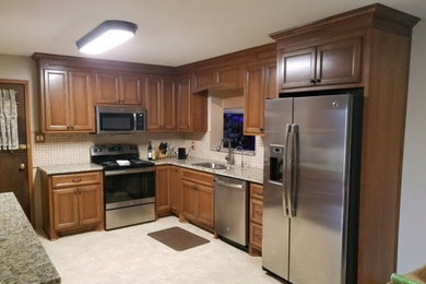 Example of a small classic l-shaped porcelain tile and beige floor eat-in kitchen design in Other with an undermount sink, recessed-panel cabinets, medium tone wood cabinets, granite countertops, beige backsplash, stone tile backsplash, stainless steel appliances and no island