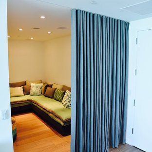 Exemple d'une petite salle de cinéma bord de mer fermée avec un mur blanc, un sol en bois foncé et un téléviseur encastré.