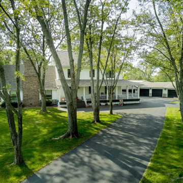 Luxury Farmhouse Exterior with Wrap-Around Porch & Tree-Lined Drive