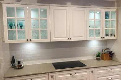 Photo of a large country galley open plan kitchen in Melbourne with raised-panel cabinets, white cabinets, quartz benchtops, white splashback, subway tile splashback, stainless steel appliances and with island.