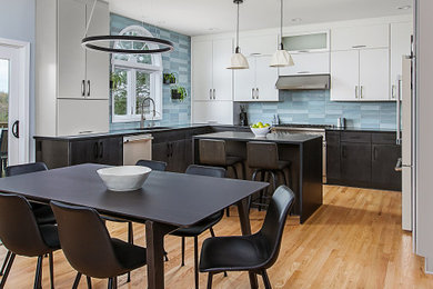 Example of a large trendy u-shaped light wood floor and beige floor eat-in kitchen design in Detroit with an undermount sink, flat-panel cabinets, quartz countertops, blue backsplash, ceramic backsplash, stainless steel appliances, an island and black countertops