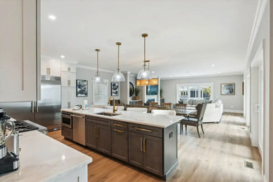 Eat-in kitchen - mid-sized transitional l-shaped laminate floor and beige floor eat-in kitchen idea in Atlanta with shaker cabinets, white cabinets, laminate countertops, white backsplash, an island, white countertops, a drop-in sink, granite backsplash and stainless steel appliances