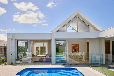 Design ideas for a mid-sized contemporary one-storey brick white house exterior in Geelong with a gable roof, a metal roof and a white roof.