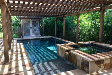 Photo of a mid-sized tropical backyard custom-shaped lap pool in Austin with a hot tub and natural stone pavers.