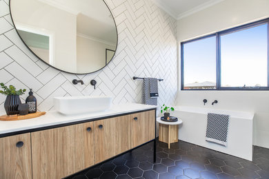 Design ideas for a scandinavian bathroom in Melbourne with flat-panel cabinets, light wood cabinets, a corner tub, white tile, white walls, a vessel sink, black floor and white benchtops.