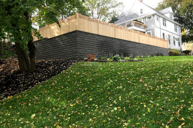 Photo of a large backyard garden in Boston with a retaining wall.