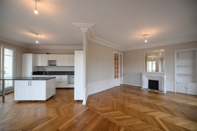 Réalisation d'une grande cuisine américaine parallèle design avec un évier 1 bac, un placard à porte persienne, des portes de placard blanches, un plan de travail en quartz, une crédence grise, une crédence en dalle de pierre, un électroménager blanc, parquet clair, îlot, un sol marron et un plan de travail gris.