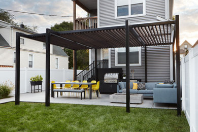 This is an example of a mid-sized contemporary full sun backyard landscaping in Chicago with a pergola for summer.
