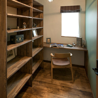 World-inspired home office and library in Nagoya with blue walls, medium hardwood flooring, a built-in desk and brown floors.