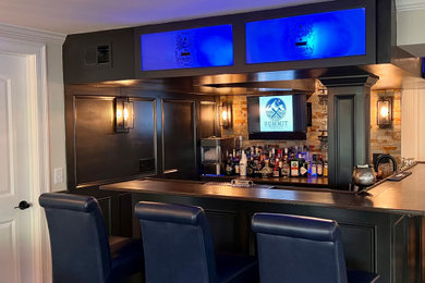 Example of a large classic walk-out laminate floor, brown floor, tray ceiling and wainscoting basement design in Providence with a bar, white walls and a standard fireplace