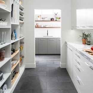 На фото: большие параллельные кухни в стиле современная классика с кладовкой, врезной раковиной, плоскими фасадами, белыми фасадами, мраморной столешницей, белым фартуком, техникой из нержавеющей стали, полом из сланца и черным полом