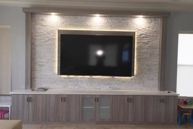 Imagen de sala de estar abierta actual grande con paredes grises y televisor colgado en la pared
