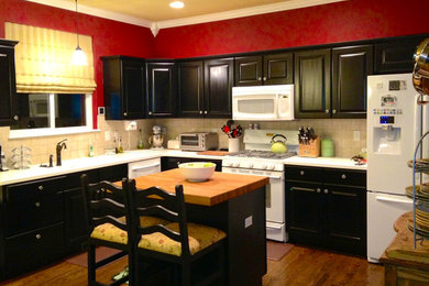Kitchen - medium tone wood floor kitchen idea in Denver with black cabinets, beige backsplash and white appliances