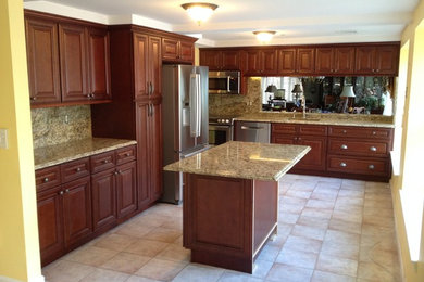 Photo of a large traditional l-shaped separate kitchen in Boston with an undermount sink, raised-panel cabinets, dark wood cabinets, granite benchtops, brown splashback, stone slab splashback, stainless steel appliances, porcelain floors and with island.