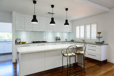 Modern kitchen in Perth with white cabinets, solid surface benchtops, glass sheet splashback and with island.
