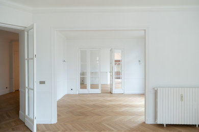 Aménagement d'une grande salle de séjour moderne ouverte avec un mur blanc, parquet clair et un sol beige.
