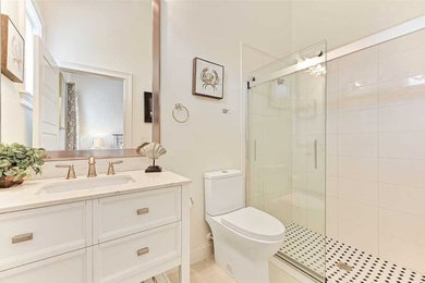Bathroom - mid-sized shabby-chic style white tile and ceramic tile terrazzo floor and beige floor bathroom idea in Orlando with raised-panel cabinets, white cabinets, a two-piece toilet, white walls, a drop-in sink and quartz countertops