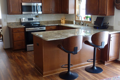 Kitchen - large transitional u-shaped kitchen idea in Milwaukee with a double-bowl sink, recessed-panel cabinets, dark wood cabinets, granite countertops, beige backsplash, ceramic backsplash, stainless steel appliances and beige countertops