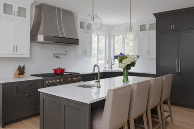 Example of a transitional l-shaped light wood floor and beige floor kitchen design in DC Metro with an undermount sink, shaker cabinets, gray cabinets, white backsplash, stone slab backsplash, paneled appliances, an island and white countertops