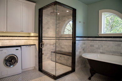 Photo of a large master bathroom in New York with a claw-foot tub, a corner shower, gray tile and a hinged shower door.
