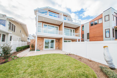 Example of a large beach style brown three-story wood house exterior design in Other with a hip roof and a metal roof