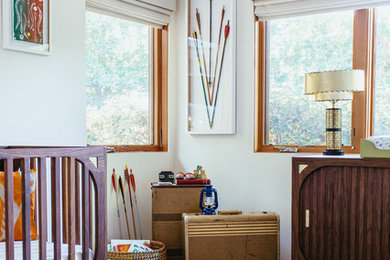 Diseño de habitación de bebé neutra retro de tamaño medio con paredes blancas y suelo de madera en tonos medios