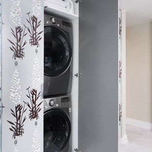 Medium sized eclectic single-wall laundry cupboard in Toronto with flat-panel cabinets, grey cabinets, grey walls, marble flooring, a concealed washer and dryer and white floors.