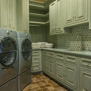 ルイビルの大きいラスティックスタイルのおしゃれな家事室 (シングルシンク、レイズドパネル扉のキャビネット、ヴィンテージ仕上げキャビネット、左右配置の洗濯機・乾燥機、緑の壁) の写真