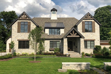 This is an example of a traditional two-storey beige house exterior in Chicago with stone veneer and a gable roof.