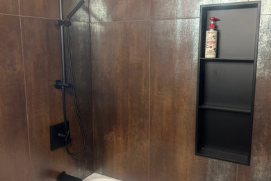 Bathroom - mid-sized contemporary brown tile and wood-look tile ceramic tile, gray floor and single-sink bathroom idea in Other with flat-panel cabinets, black cabinets, a two-piece toilet, beige walls, a wall-mount sink, solid surface countertops, white countertops, a niche and a freestanding vanity