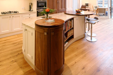 Inspiration for a large traditional l-shaped eat-in kitchen in Edinburgh with a double-bowl sink, beaded inset cabinets, white cabinets, granite benchtops, stainless steel appliances, light hardwood floors, with island and white splashback.
