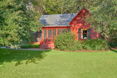 Photo of a mid-sized traditional one-storey red house exterior with wood siding, a gable roof and a metal roof.