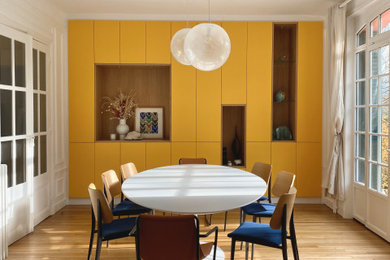 Cette photo montre une grande salle à manger tendance fermée avec parquet clair, un mur blanc et un sol beige.