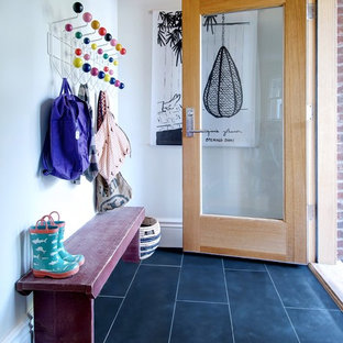 トロントの中サイズの片開きドアコンテンポラリースタイルのおしゃれなマッドルーム (スレートの床、黒い床、白い壁、木目調のドア) の写真