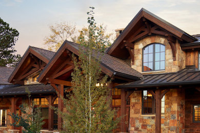 Imagen de fachada de casa multicolor y marrón rústica extra grande de dos plantas con revestimiento de piedra, tejado a dos aguas, tejado de teja de madera y teja