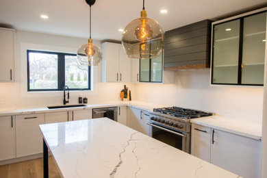 This is an example of a medium sized modern l-shaped kitchen/diner in Toronto with shaker cabinets, quartz worktops, light hardwood flooring, an island and white worktops.