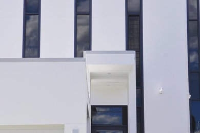 Modern inredning av ett mycket stort vitt hus, med tre eller fler plan, platt tak och tak i metall