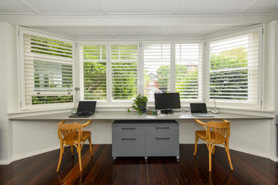 Design ideas for a medium sized eclectic study in Sydney with white walls, dark hardwood flooring and a built-in desk.