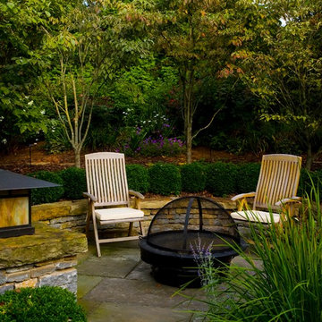 Copper bowl fire pit on bluestone terrace with limestone sit wall.