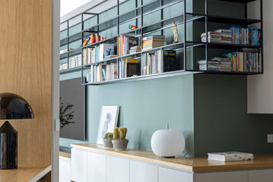 Idee per un soggiorno minimal di medie dimensioni e aperto con libreria, pareti verdi, parquet chiaro, TV a parete e pavimento beige