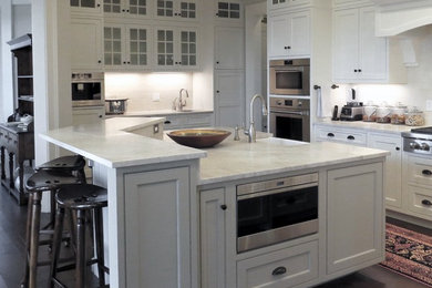 Elegant u-shaped dark wood floor and brown floor open concept kitchen photo in Bridgeport with a farmhouse sink, beaded inset cabinets, white cabinets, white backsplash, ceramic backsplash, stainless steel appliances, an island and white countertops