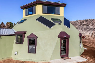 Small southwestern green two-story stucco house exterior idea in Other with a hip roof and a metal roof