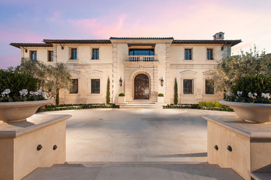 Example of a large tuscan beige two-story stone house exterior design in Orange County
