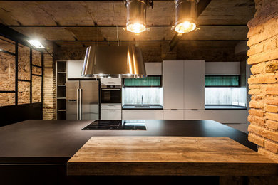 Idee per una cucina minimalista di medie dimensioni con lavello integrato, ante lisce, ante bianche, elettrodomestici in acciaio inossidabile, pavimento in cemento, pavimento grigio, top grigio e travi a vista