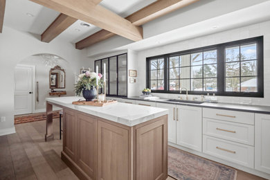Example of a large transitional l-shaped medium tone wood floor, multicolored floor and exposed beam eat-in kitchen design in Detroit with an undermount sink, shaker cabinets, white cabinets, quartz countertops, white backsplash, subway tile backsplash, stainless steel appliances, two islands and white countertops