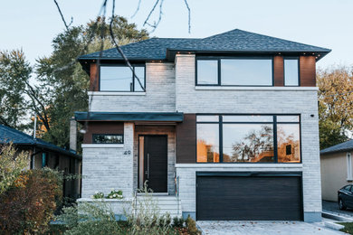 Ejemplo de fachada de casa gris y negra contemporánea grande de dos plantas con revestimiento de piedra, tejado a dos aguas, tejado de teja de madera y panel y listón