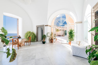 Esempio di un ingresso o corridoio mediterraneo con pareti bianche, pavimento in marmo, una porta a due ante, una porta bianca, pavimento grigio e soffitto a volta